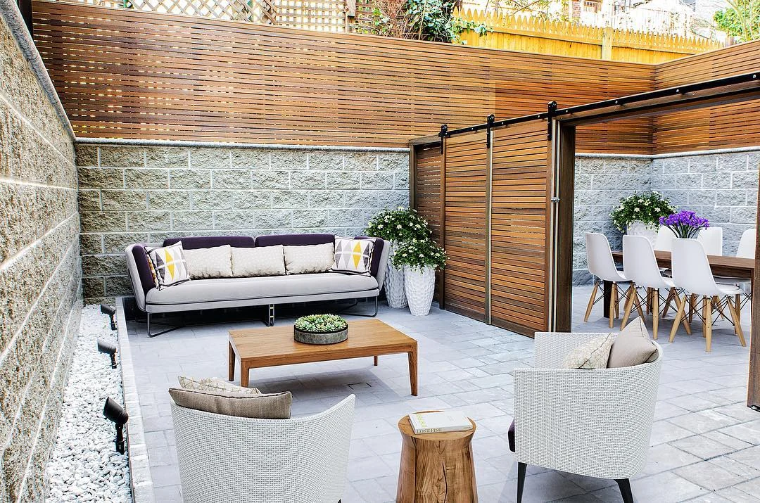 Finished courtyard with paving, lounge and dining areas separated by sliding horizontal privacy screens
